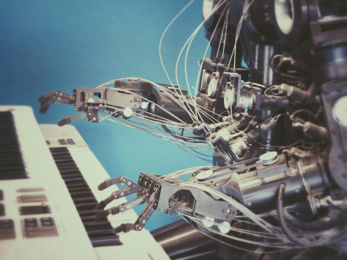 Robot hands playing a keyboard against a blue background, with various wires and mechanical parts visible, suggesting a futuristic mood.